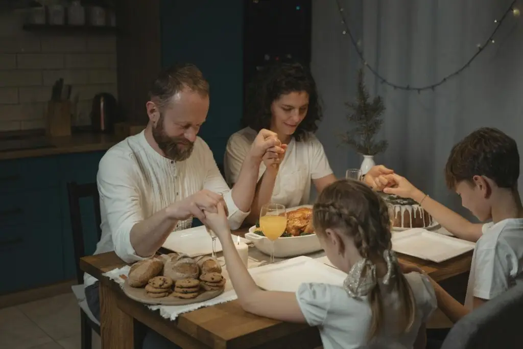 Meaning and Importance of Family Values for Primary 5 1 family values: holding hands and praying over a dinner table with turkey and cookies during festival party.