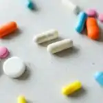 Meaning Of Overdose for Primary 1 4 Close-up view of assorted colorful pills and tablets scattered on a white surface.